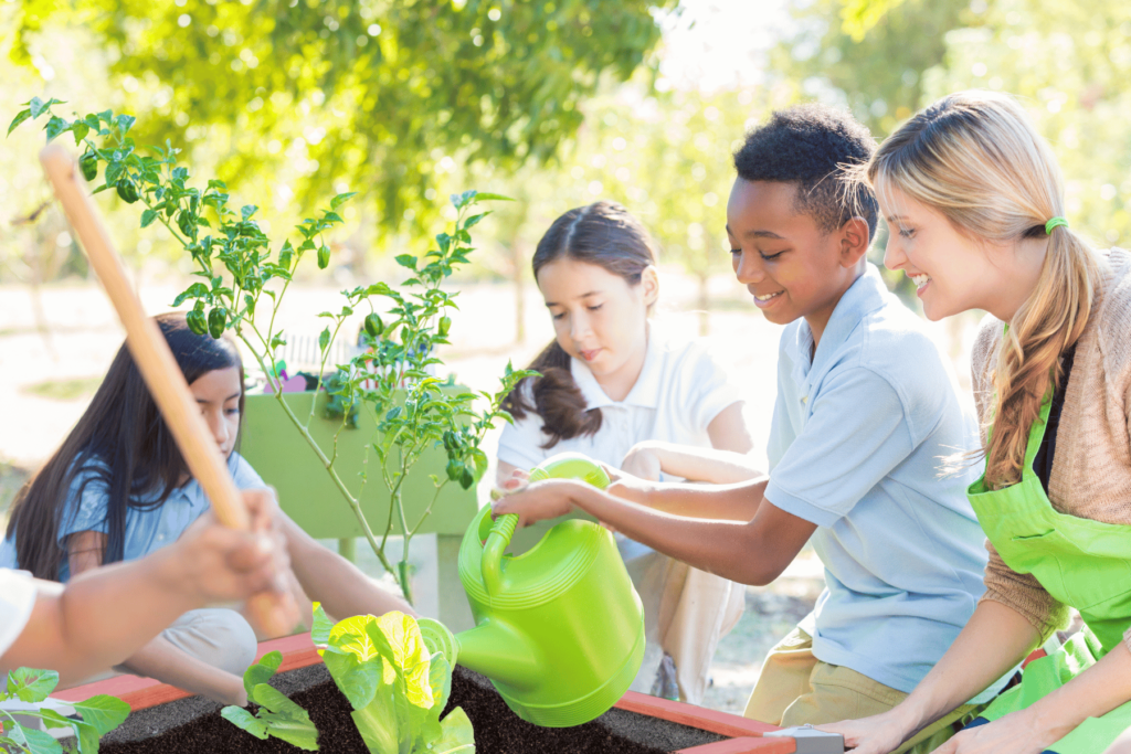 Teacher and students water a plant in a Durable GreenBed Garden Kit