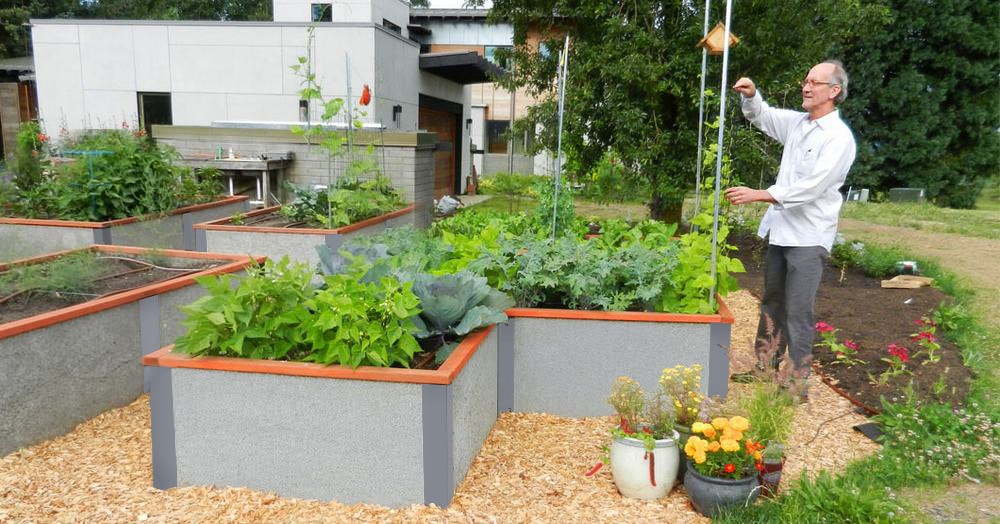 hombre que atiende camas de jardín elevadas al lado de un centro para personas mayores